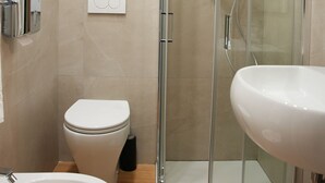 Un baño moderno con ducha acristalada, inodoro, bidé y lavabo.
