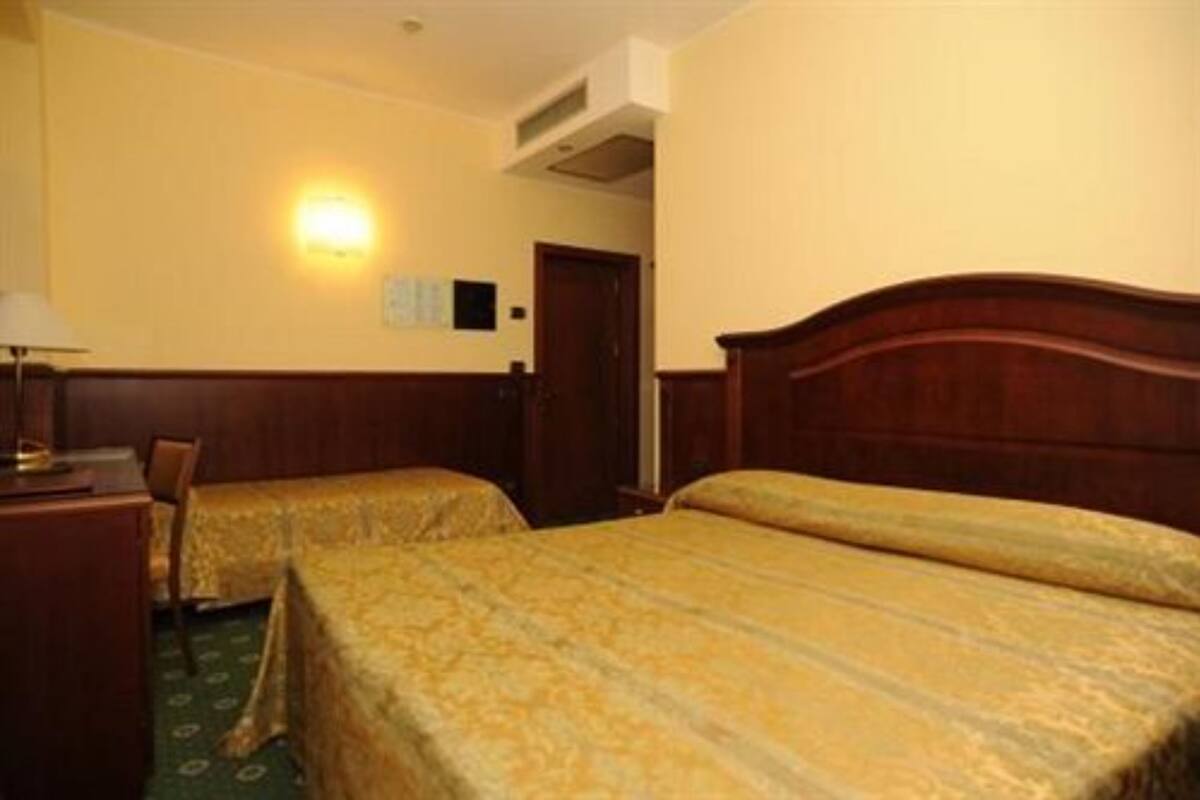 Una habitación de hotel con dos camas, un escritorio y una lámpara.