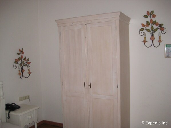 Una habitación con un armario grande, una mesita de noche con lámpara y un adorno en la pared.