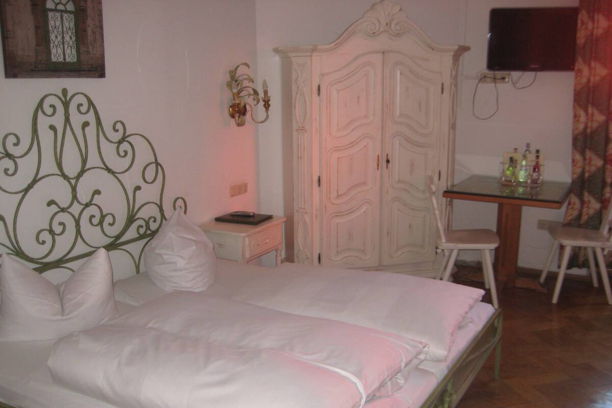 A bedroom with a bed, a desk, and a wardrobe.