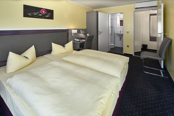 A hotel room with a large bed, a desk, a chair, and a bathroom.