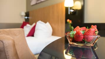 Ein Hotelzimmer mit einem Bett, einem Nachttisch mit einer Schale Erdbeeren und einer Wandlampe.