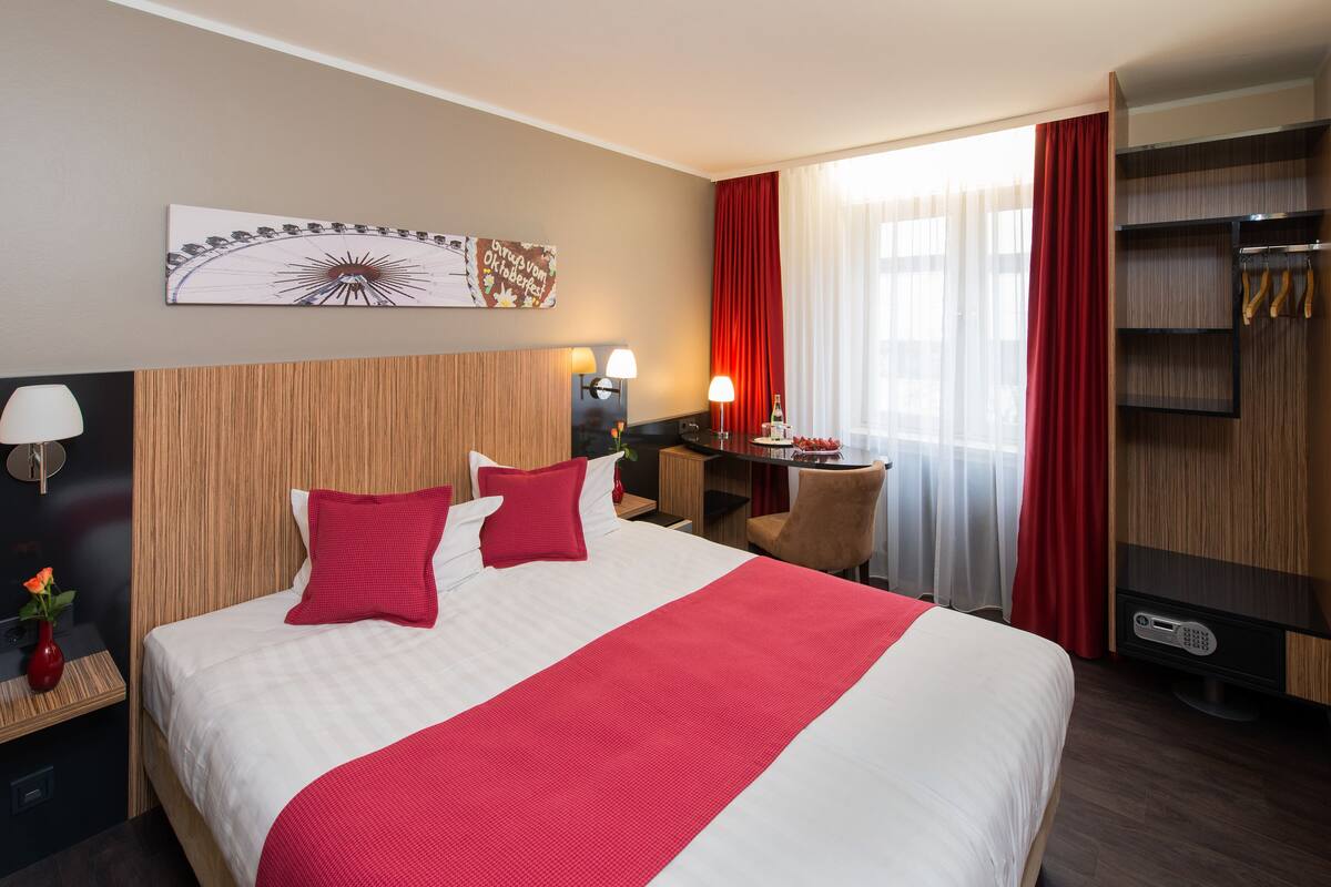 Una habitación de hotel con una cama grande, un escritorio con lámpara, un televisor y un armario.