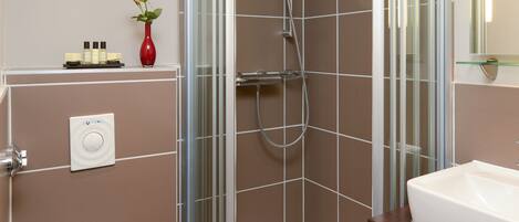 A modern bathroom with a glass-enclosed shower, a white toilet, and a sink with a mirror above it.