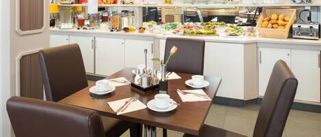 A dining area with a buffet setup, including various food items and a coffee station.