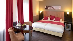 A hotel room with a bed, a table with chairs, and a minibar. - Hotel Munich City (Munich)