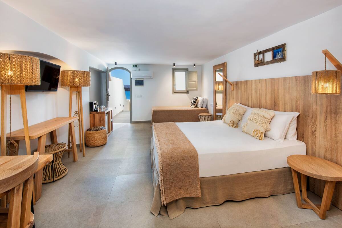 A modern hotel room with a large bed, wooden furniture, a television, and a view of the outdoors.