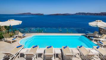 Una piscina al aire libre, sombrillas, sillones reclinables de piscina