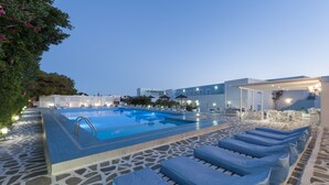 A pool area with lounge chairs, a clear pool, and a building with a modern design.