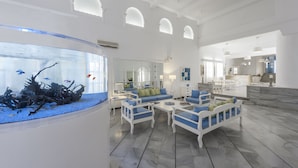 A spacious living area with a large aquarium, white furniture, and a bright, airy design.