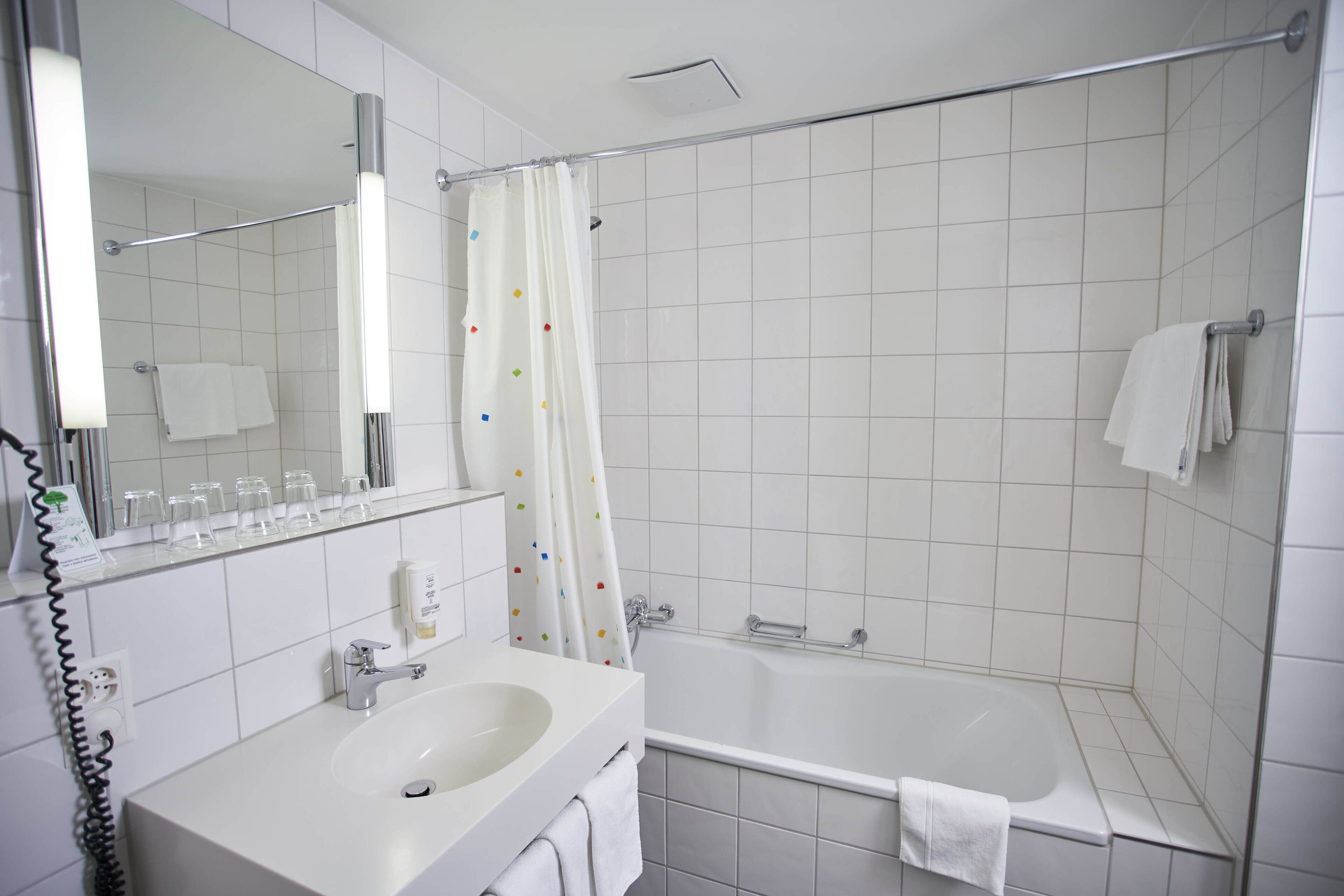 A bathroom with a white sink, mirror, and bathtub.