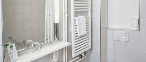 A bathroom with a white sink, mirror, toilet, and towel rack.