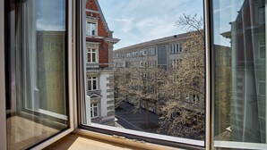A view from a window overlooking a street with buildings and trees. - Bristol Hotel (Zürich)