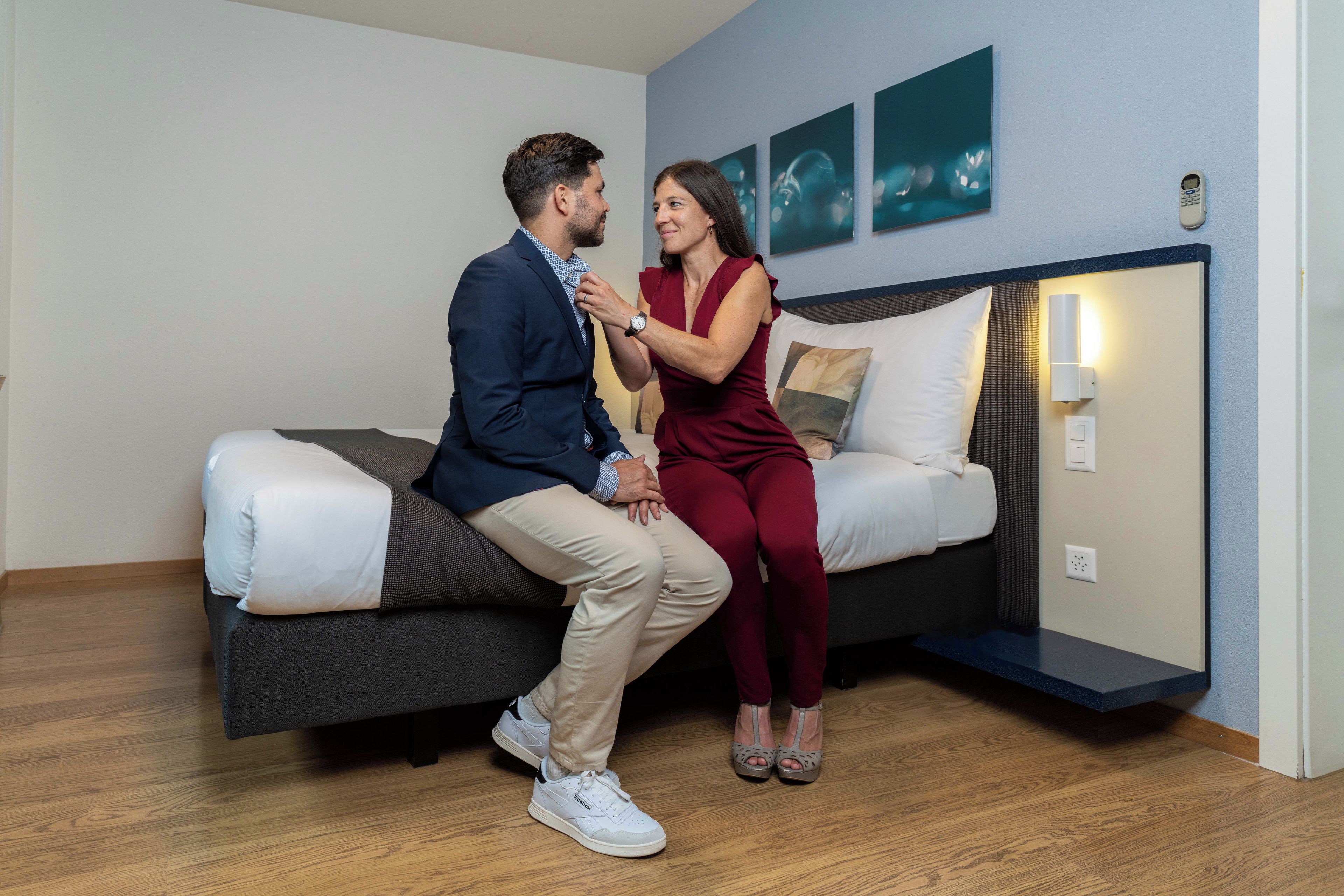 A modern room with a bed, a wall-mounted light, and artwork.
