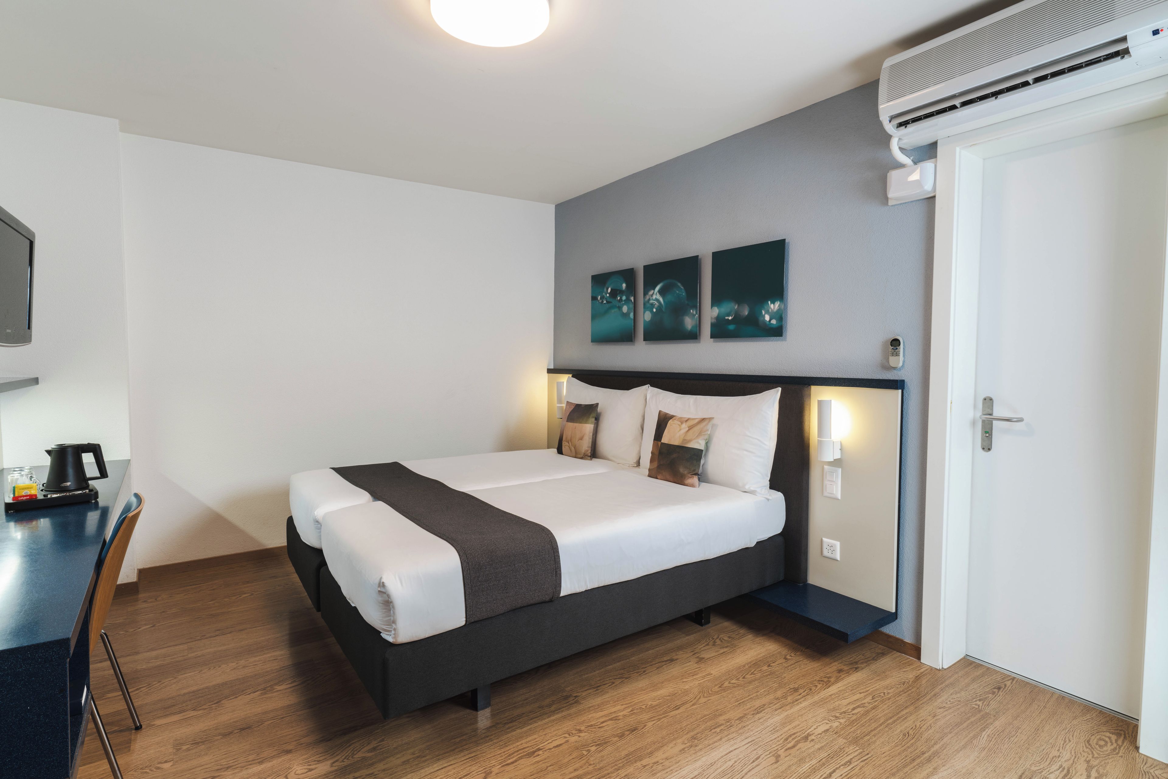 A hotel room with a bed, bedside table, and a coffee maker.