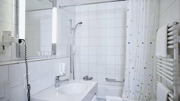A modern bathroom with a white sink, mirror, and shower.