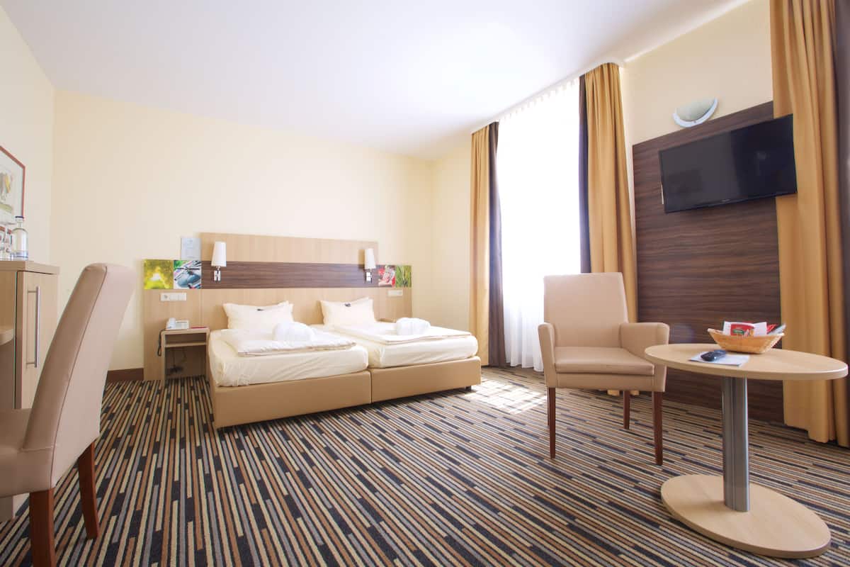 Une chambre d’hôtel équipée d’un lit, d’un bureau, d’une chaise, d’une télévision et d’une petite table.