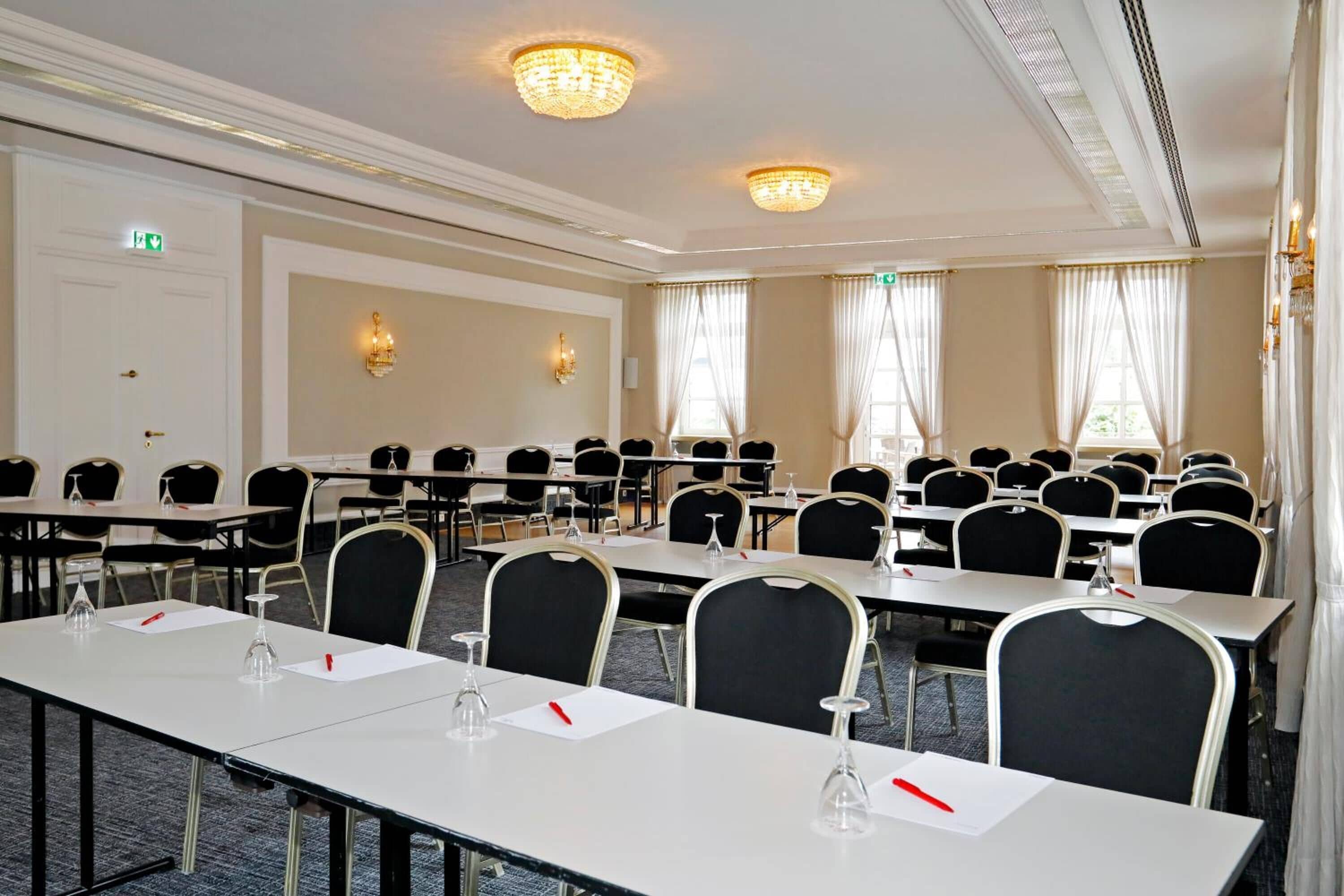 Ein Konferenzraum mit Tischen und Stühlen in Reihen, ausgestattet mit Namensschildern und Wassergläsern.