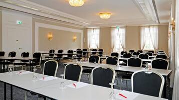 A conference room with rows of tables and chairs, equipped with nameplates and water glasses.