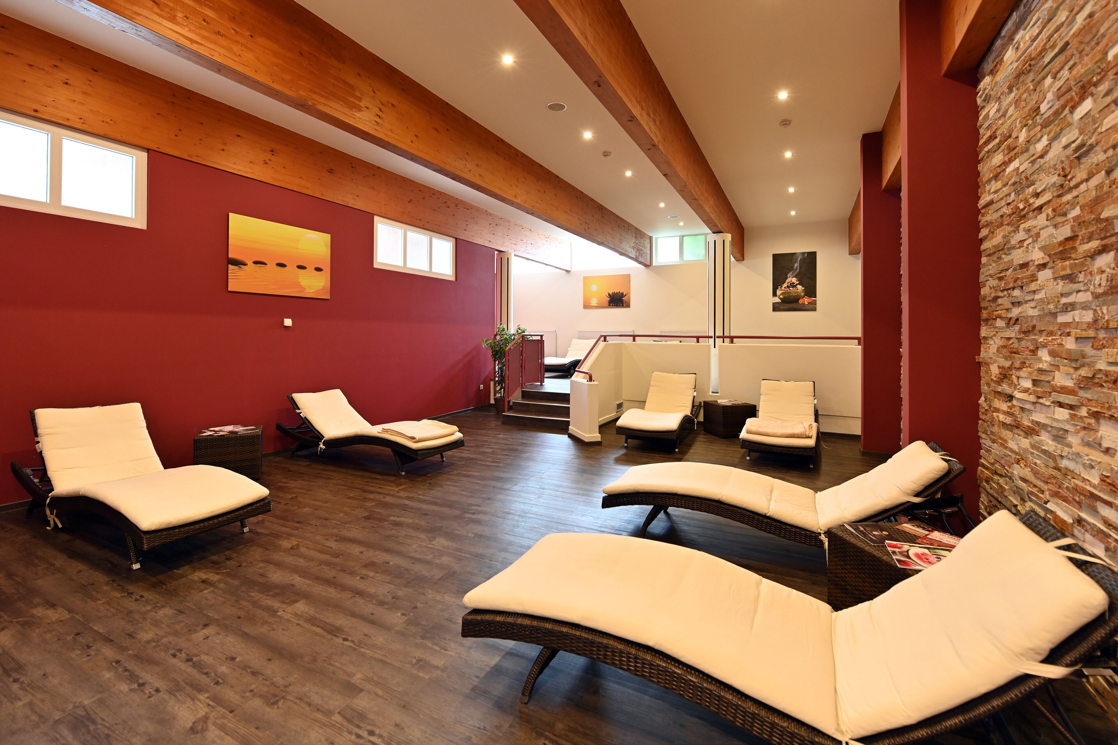 Une salle de spa avec des poutres en bois, des murs rouges et plusieurs chaises longues.