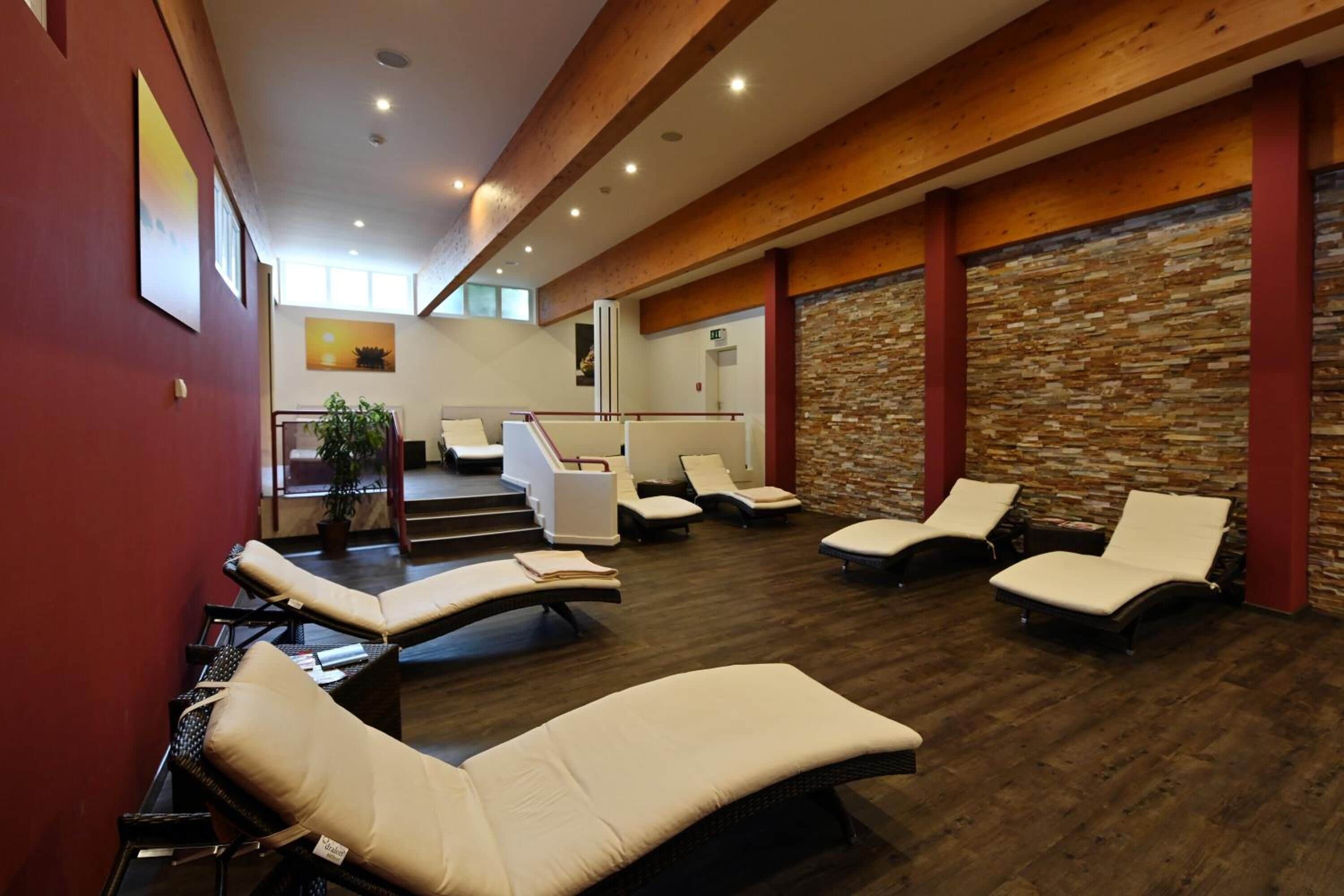 A spa area with multiple lounge chairs, a reception desk, and a stone wall.