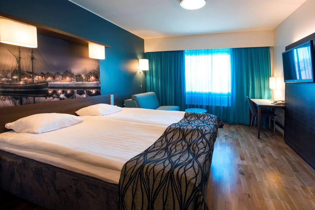 Una habitación de hotel con una cama grande, un escritorio, una silla y un televisor.