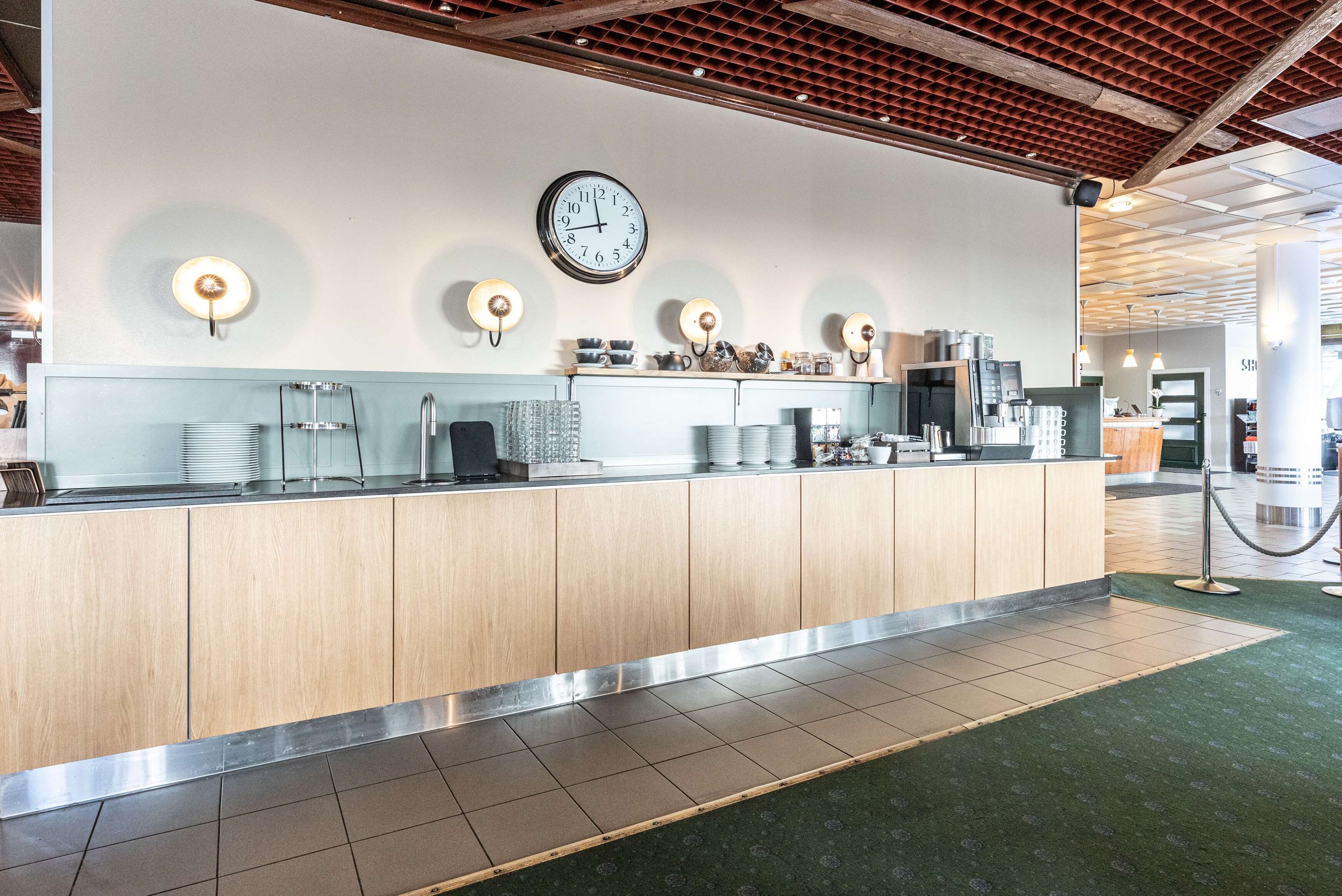 A reception area with a wooden counter, a clock, and wall-mounted light fixtures.