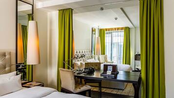 Quarto de hotel com cama, escrivaninha, cadeira, abajur e espelho.