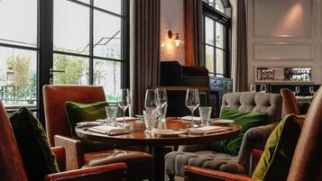 A dining area with a round table set for four, leather chairs, and a view through large windows.