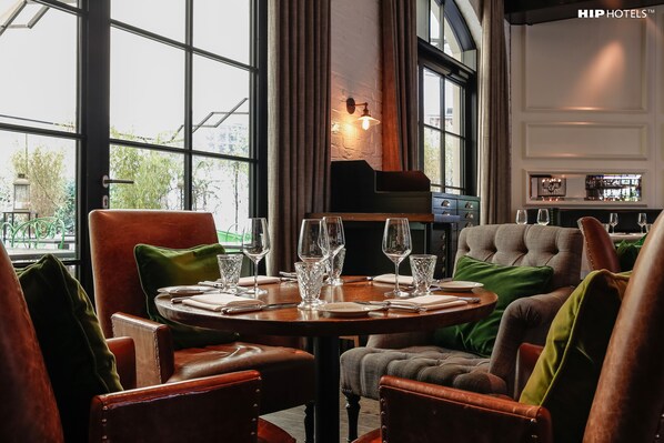 A dining area with a round table set for four, leather chairs, and a view through large windows.