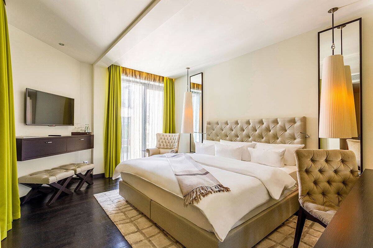 A modern hotel room with a large bed, a flat-screen TV, a desk, and a chair.