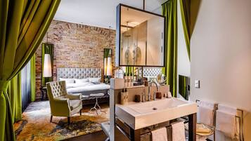Camera d'albergo moderna con parete in mattoni, un grande letto, una toeletta con specchio e una tenda verde.