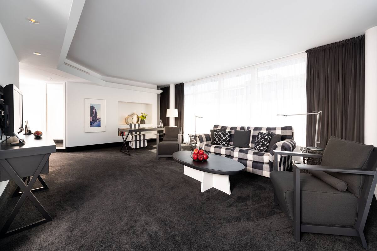 Een moderne woonkamer met een bank, fauteuil, salontafel en een eethoek met een tafel en stoelen.