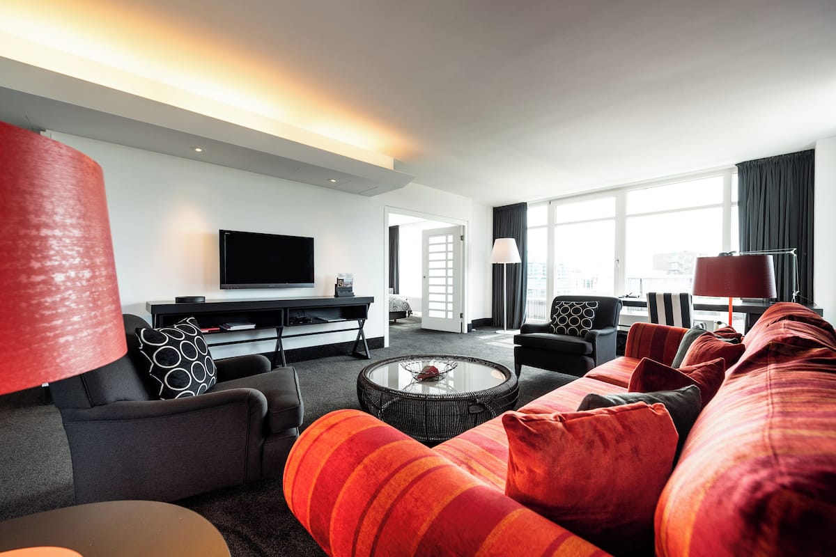 Een moderne woonkamer met een bank, een salontafel, een televisie en een groot raam.
