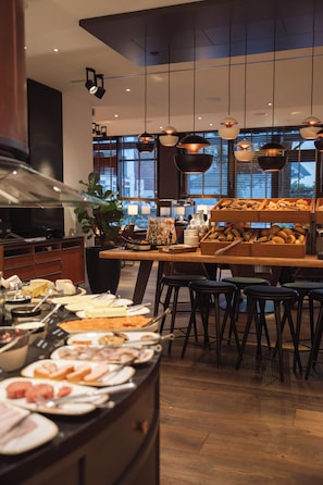 A buffet area with various food items, a large plant, and hanging pendant lights.