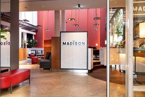 A modern lobby with a large sign reading 'The Madison,' red walls, and seating areas. - THE MADISON Hotel Hamburg (Hamburg)