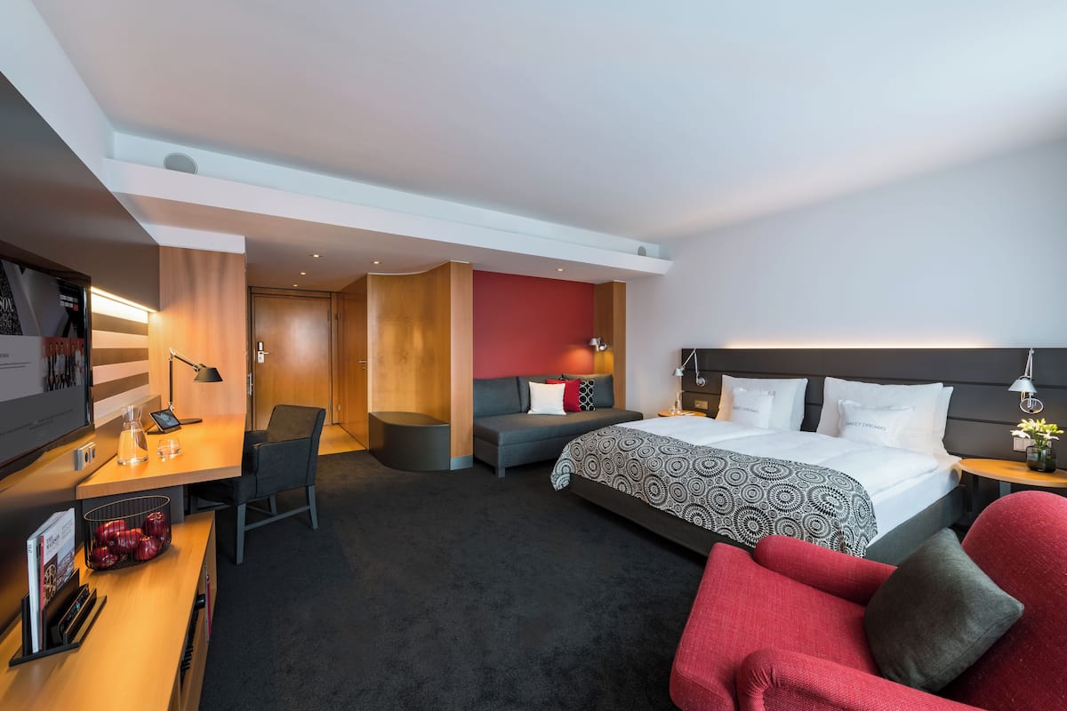 Een moderne hotelkamer met een bed, bureau en zithoek.