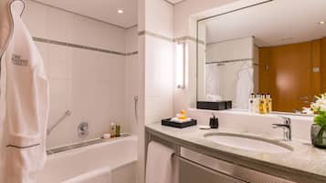 Une salle de bain moderne avec une baignoire, un grand miroir et un meuble-lavabo.