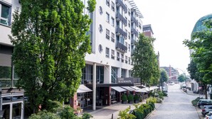 Un edificio con un cartel que dice 'The Madison' en la planta baja, rodeado de árboles y una calle empedrada.