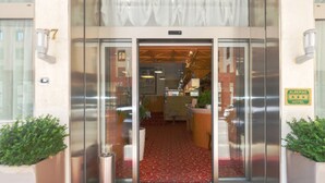 L’entrée d’un hôtel, avec un tapis rouge, des portes en verre et une enseigne indiquant le nom de l’hôtel.