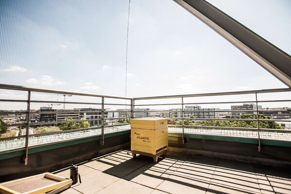 Una habitación con un amplio ventanal con vistas a un paisaje urbano, que incluye un fardo de madera con la etiqueta 'Atlantic Hotel'.