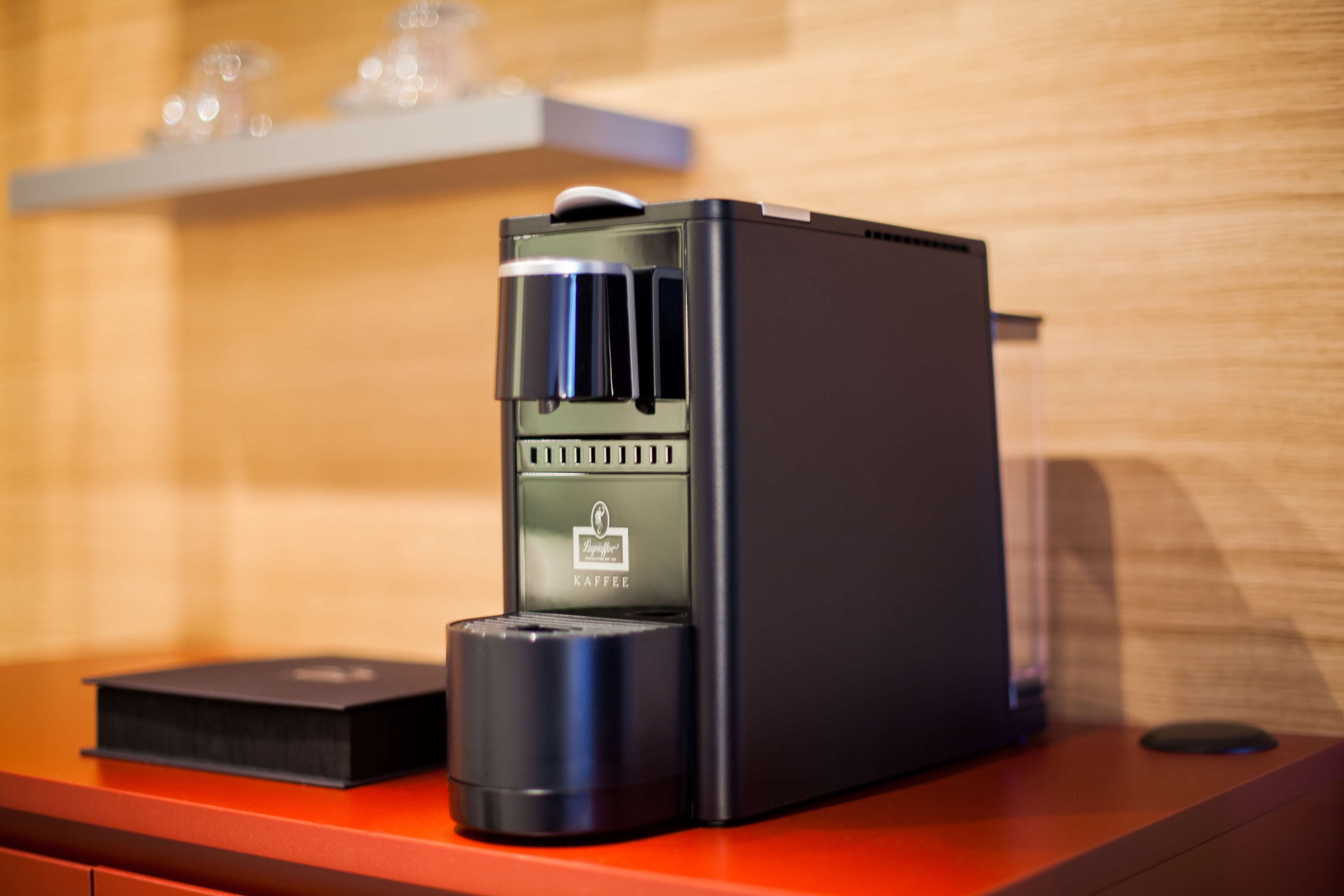 Una máquina de café espresso negra con pantalla digital sobre una encimera de madera.