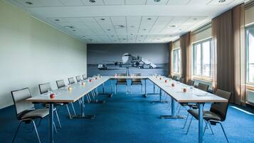Una sala conferenze con un lungo tavolo, sedie e un'ampia finestra.