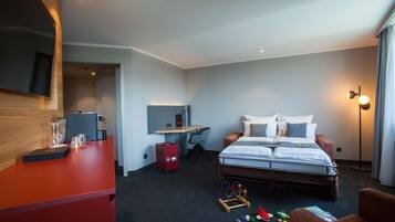 A hotel room with a bed, desk, chair, and a TV mounted on the wall.