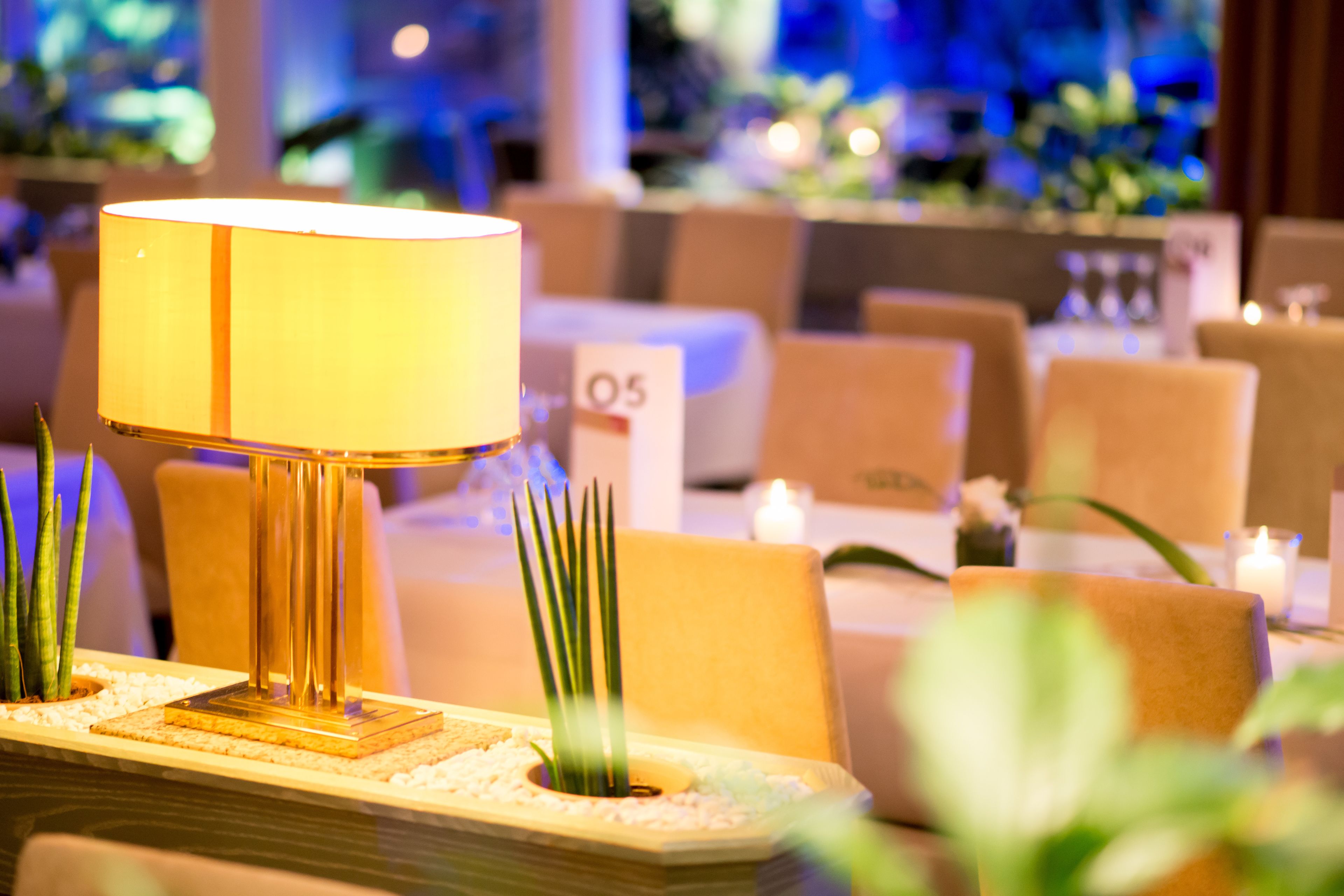 A well-lit dining area with a table lamp, chairs, and a candle.