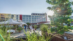 A courtyard with a modern building, outdoor seating, and potted plants.