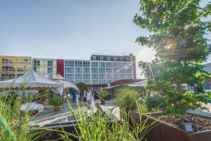 A courtyard with a modern building, outdoor seating, and potted plants. - Hotel Freizeit In (Goettingen)