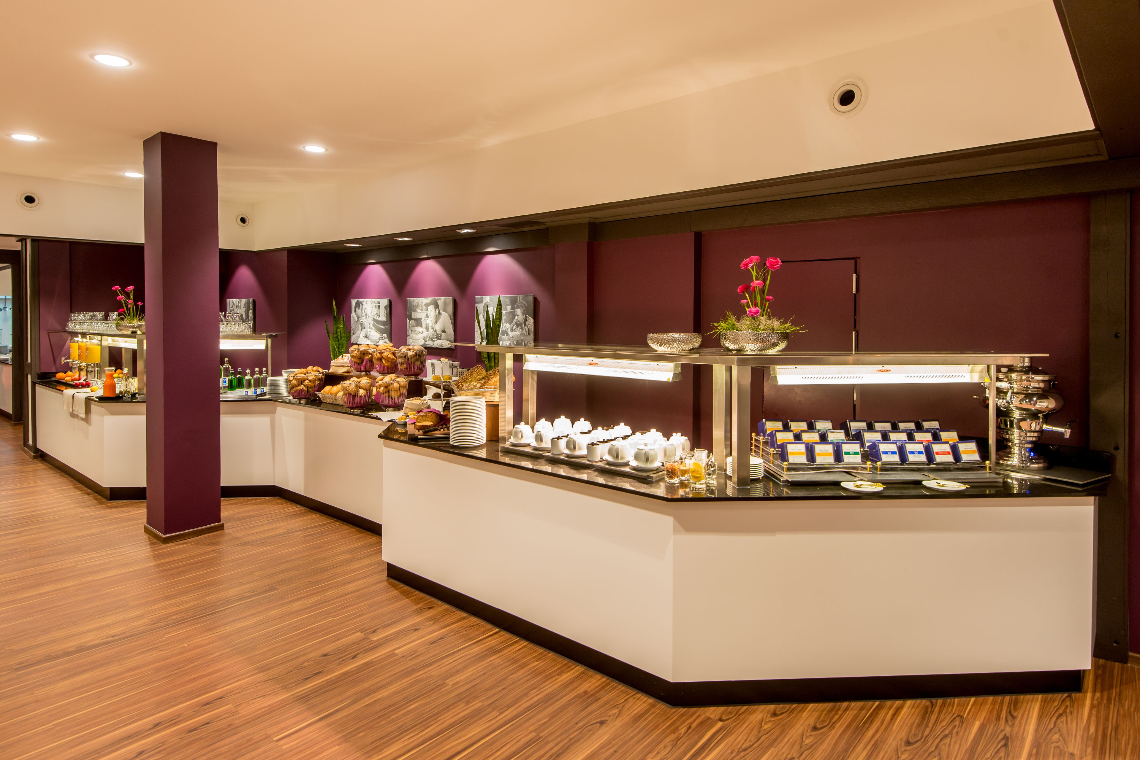 A modern hotel reception area with a marble counter, a coffee station, and a variety of food items.