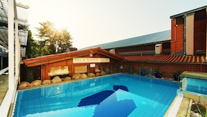 Une piscine dotée d’une terrasse en bois et d’un panneau indiquant « Blockhaus Sauna ».