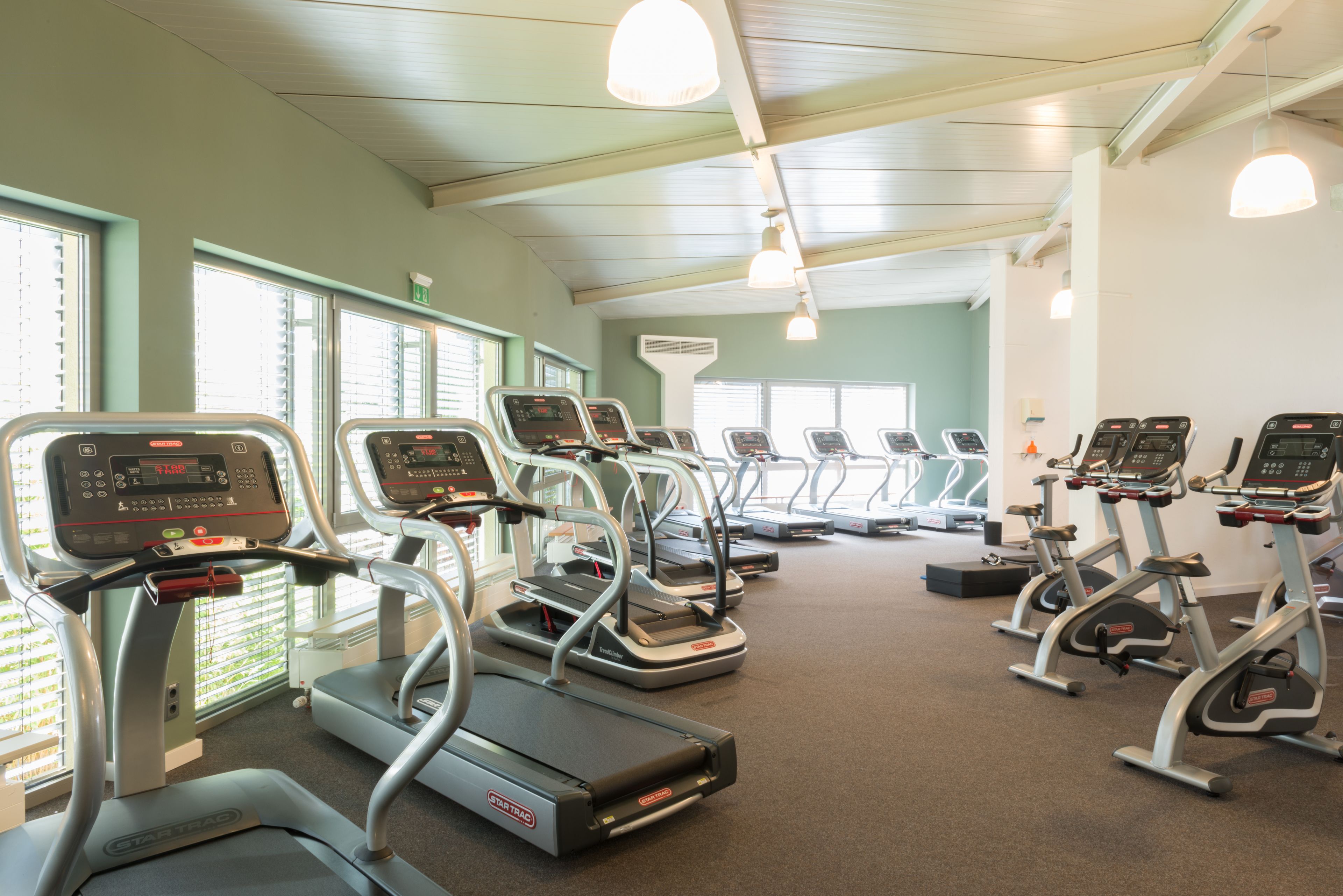 Un gimnasio con cintas de correr y equipo de ejercicio.